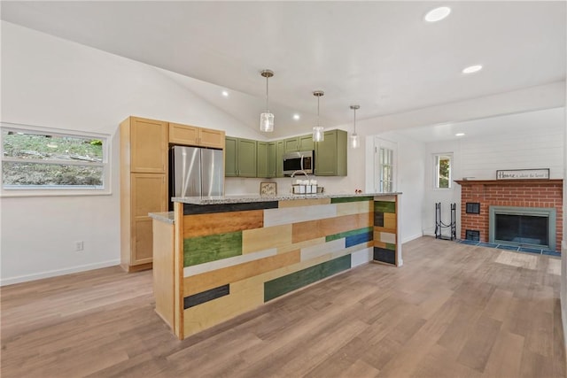 kitchen with appliances with stainless steel finishes, light stone counters, a fireplace, kitchen peninsula, and light wood-type flooring