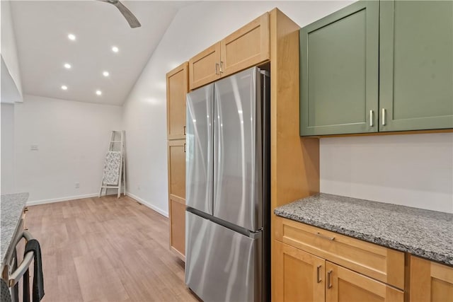 kitchen with lofted ceiling, stainless steel fridge, green cabinets, light stone countertops, and light wood-type flooring