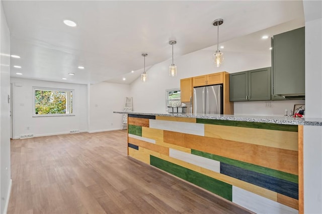 kitchen with stainless steel refrigerator, green cabinets, light hardwood / wood-style flooring, and a wealth of natural light