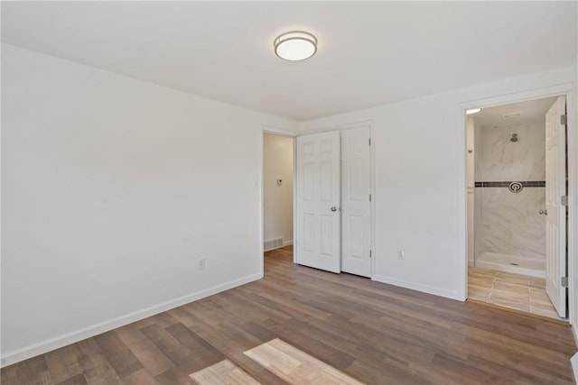 unfurnished bedroom featuring connected bathroom and wood-type flooring