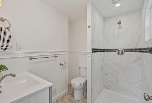 bathroom featuring a tile shower, vanity, and toilet