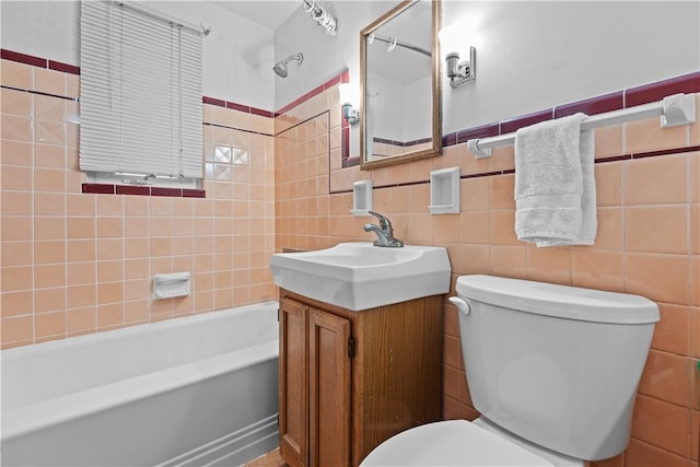 full bathroom featuring vanity, tiled shower / bath, tile walls, and toilet