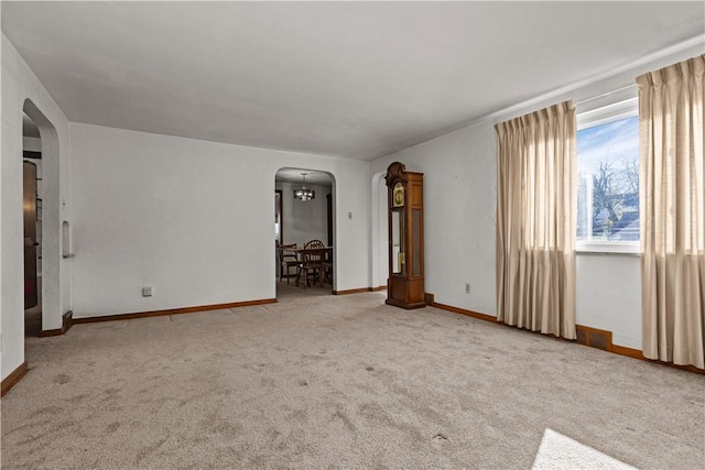 carpeted spare room featuring a chandelier