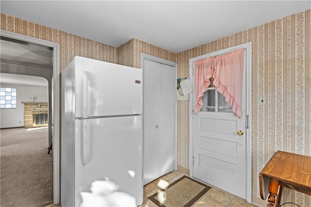 interior space with light colored carpet, a fireplace, and white fridge