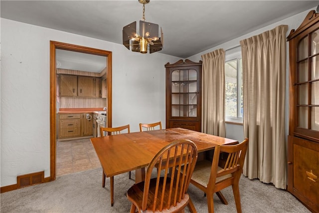 dining room featuring light carpet and a chandelier