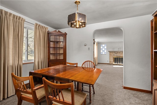 carpeted dining space featuring a chandelier and a fireplace