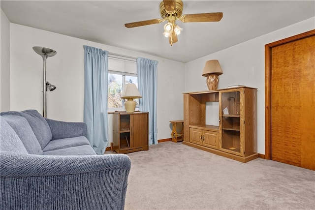 living area with light colored carpet and ceiling fan