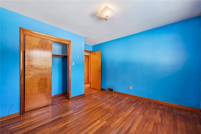 unfurnished bedroom with dark wood-type flooring and a closet