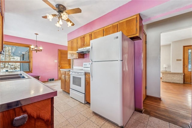 kitchen featuring white appliances, sink, decorative light fixtures, and ceiling fan with notable chandelier