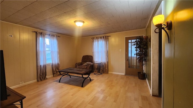 living area featuring ornamental molding, wooden walls, and light wood-type flooring