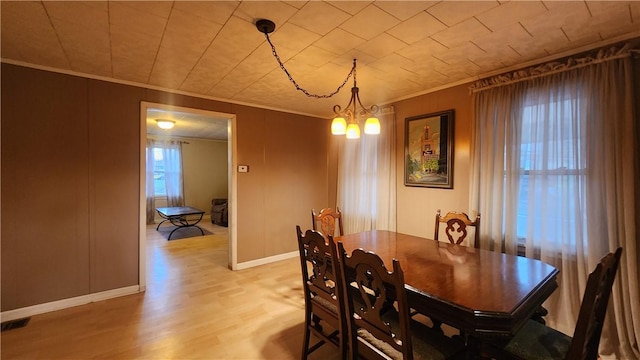 dining space featuring an inviting chandelier, ornamental molding, and light wood-type flooring