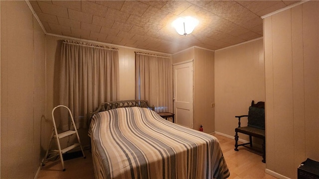 bedroom featuring ornamental molding and wood walls