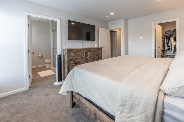 bedroom with a spacious closet, carpet floors, and ensuite bathroom