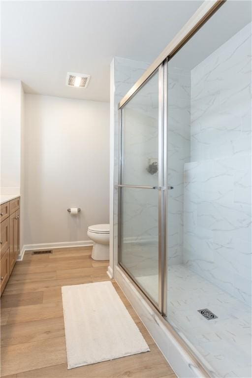 bathroom featuring hardwood / wood-style flooring, vanity, toilet, and a shower with door