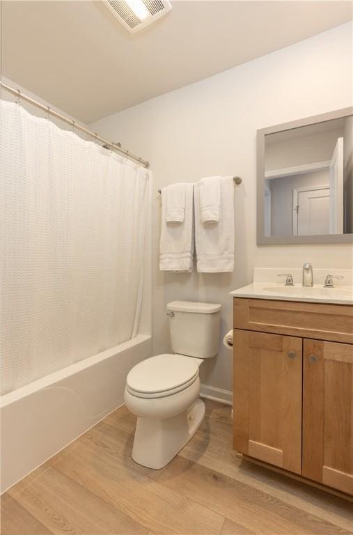 full bathroom featuring wood-type flooring, shower / tub combo, vanity, and toilet