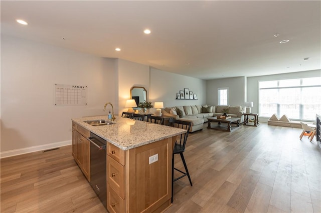 kitchen featuring sink, light hardwood / wood-style flooring, dishwasher, and a center island with sink