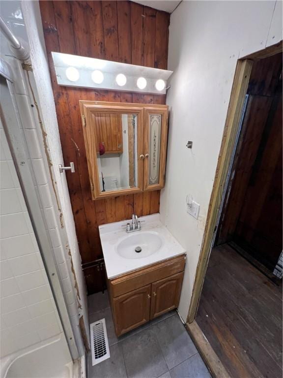 bathroom with vanity, tile patterned flooring, and wooden walls