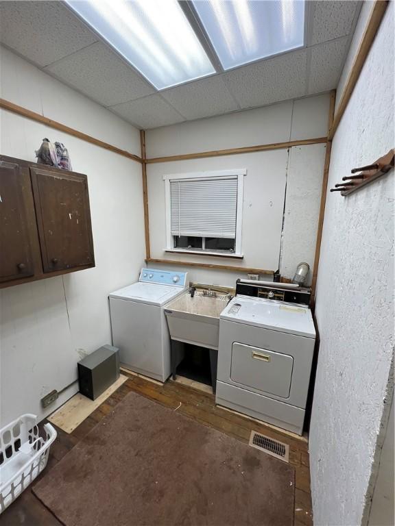 clothes washing area with dark hardwood / wood-style floors, cabinets, sink, and washing machine and dryer