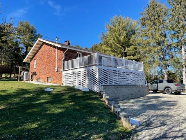 view of side of property featuring a deck, a lawn, and central air condition unit