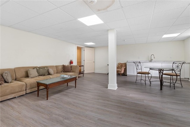 living room with hardwood / wood-style flooring, a paneled ceiling, and sink