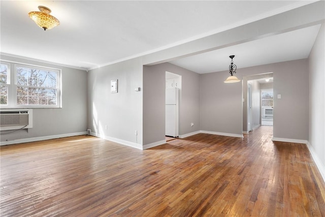 unfurnished living room featuring a wall mounted air conditioner, hardwood / wood-style flooring, and ornamental molding