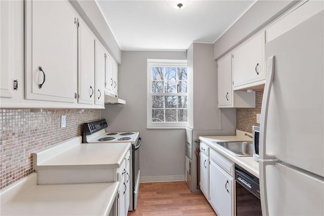 kitchen with tasteful backsplash, white cabinetry, sink, white fridge, and electric stove