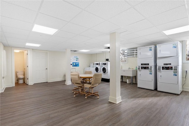 dining area with stacked washer / dryer, separate washer and dryer, hardwood / wood-style floors, and a drop ceiling