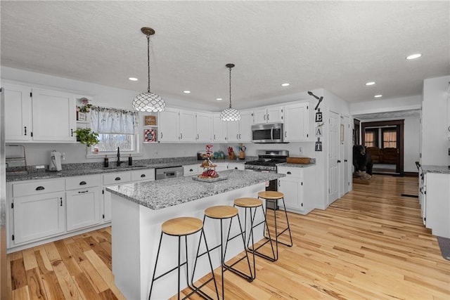 kitchen featuring white cabinetry, stainless steel appliances, light stone counters, and a kitchen island