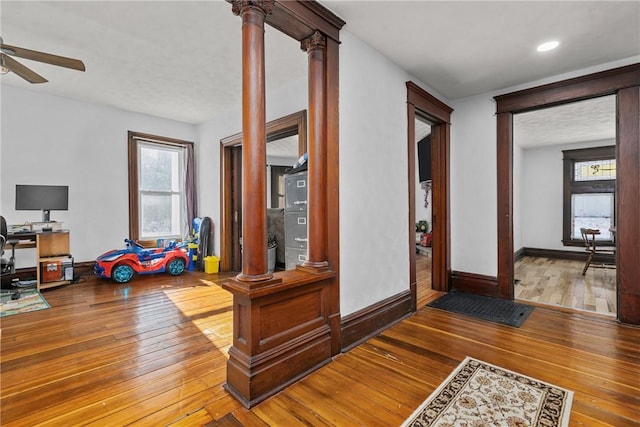 hallway featuring wood-type flooring and decorative columns