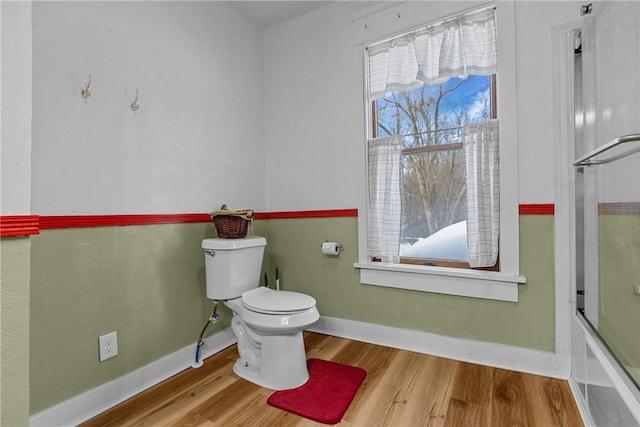 bathroom featuring hardwood / wood-style floors, shower / bath combination with glass door, and toilet