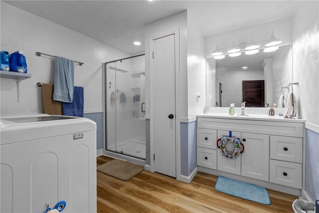 bathroom featuring an enclosed shower, vanity, washer / dryer, and wood-type flooring