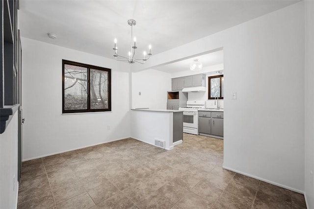 kitchen featuring gray cabinetry, kitchen peninsula, white gas stove, and an inviting chandelier