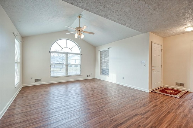 empty room featuring ceiling fan, lofted ceiling, a textured ceiling, and dark hardwood / wood-style flooring