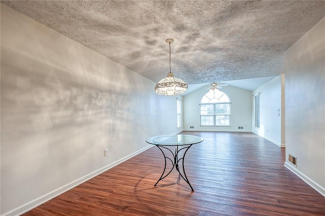 unfurnished dining area featuring vaulted ceiling and dark hardwood / wood-style floors