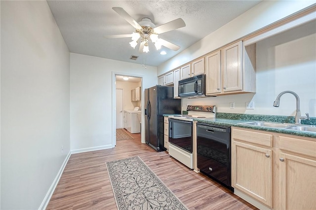 kitchen featuring light brown cabinetry, sink, washing machine and dryer, light hardwood / wood-style floors, and black appliances