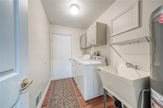 washroom with dark hardwood / wood-style floors, sink, cabinets, independent washer and dryer, and a textured ceiling