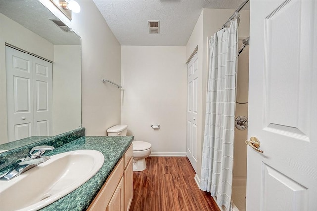 bathroom featuring vanity, wood-type flooring, toilet, and a textured ceiling