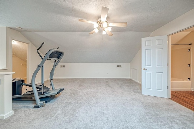 exercise area with ceiling fan, vaulted ceiling, a textured ceiling, and carpet flooring