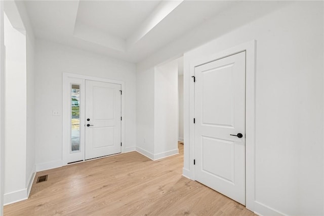 entrance foyer featuring light wood finished floors, visible vents, baseboards, and a tray ceiling