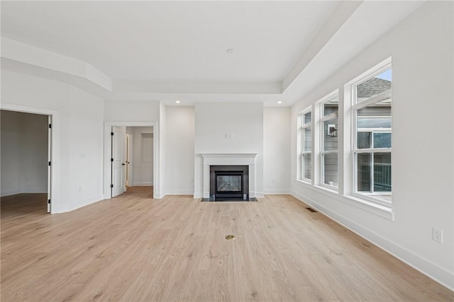 unfurnished living room with light wood finished floors, visible vents, baseboards, a fireplace with flush hearth, and recessed lighting