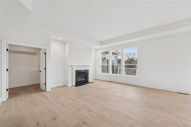 unfurnished living room featuring visible vents, baseboards, recessed lighting, a high end fireplace, and light wood-type flooring