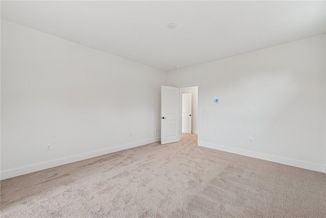 unfurnished room with baseboards and light carpet