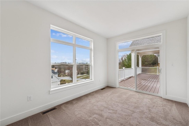 spare room with carpet flooring, baseboards, and visible vents