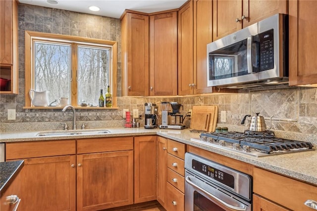 kitchen featuring light stone counters, appliances with stainless steel finishes, sink, and decorative backsplash