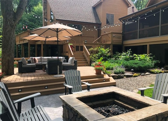 view of patio featuring a sunroom, stairway, a deck, and an outdoor living space with a fire pit