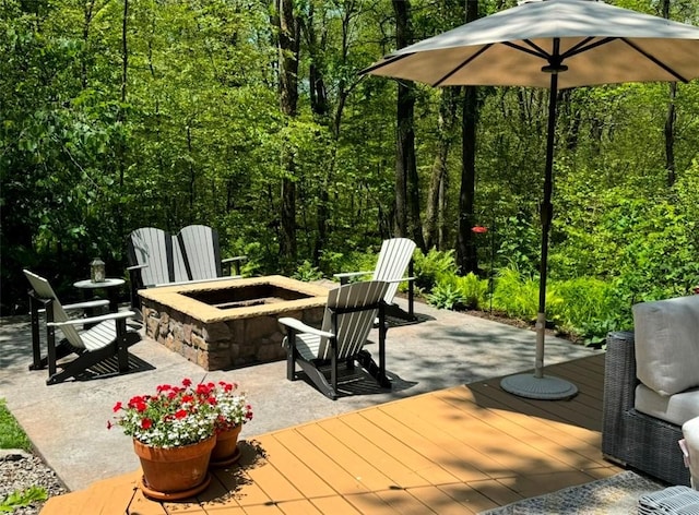 view of patio / terrace with a fire pit, a deck, and a wooded view