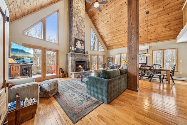 living room featuring a stone fireplace, wooden ceiling, ceiling fan, and light hardwood / wood-style flooring