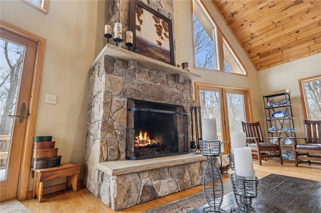 living room with a stone fireplace, wood-type flooring, high vaulted ceiling, and wooden ceiling