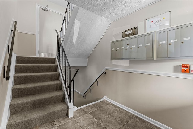 staircase with tile patterned flooring, vaulted ceiling, a mail area, and a textured ceiling