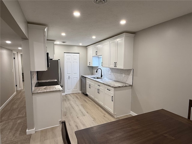 kitchen featuring sink, tasteful backsplash, dishwasher, light stone countertops, and white cabinets